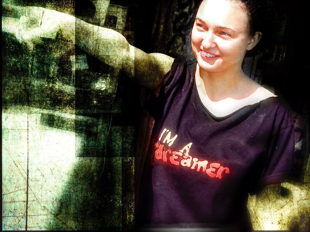 Smiling young woman wearing an I am a dreamer shirt pointing with her finger
