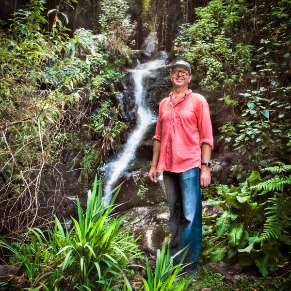 Alexius Jorgensen standing in the mountains with a small flowing waterfall background