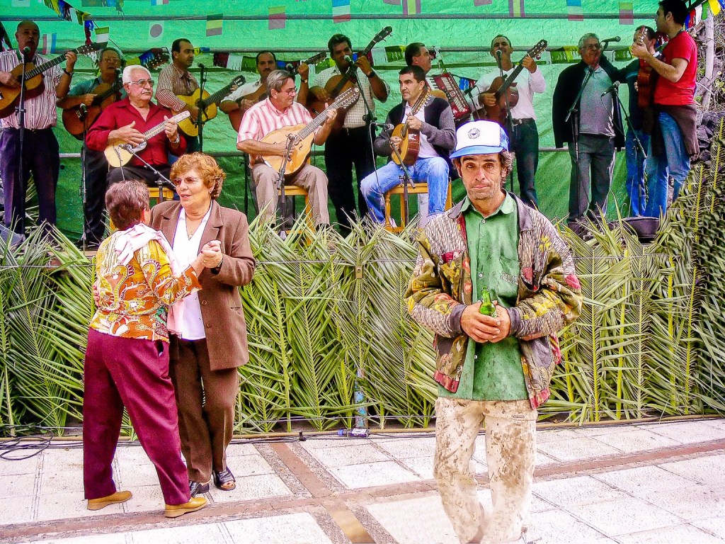 Colourfully dressed man dancing uniquely contrasted by a traditional couple and a live stage band