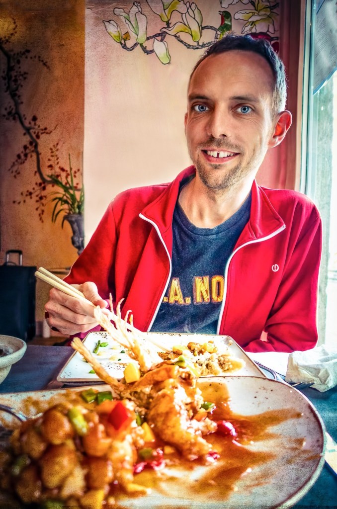 A man eating food in a Chinese restaurant representing the unedited present moment
