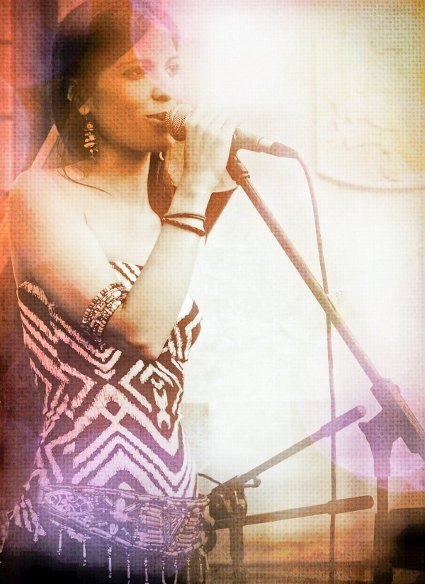 Young woman looking happy and in sync while singing a song on a stage microphone setup