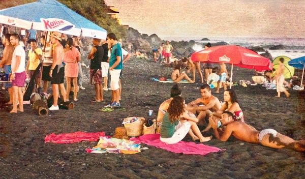 A laid back evening beach party scene with people relaxing by the ocean side