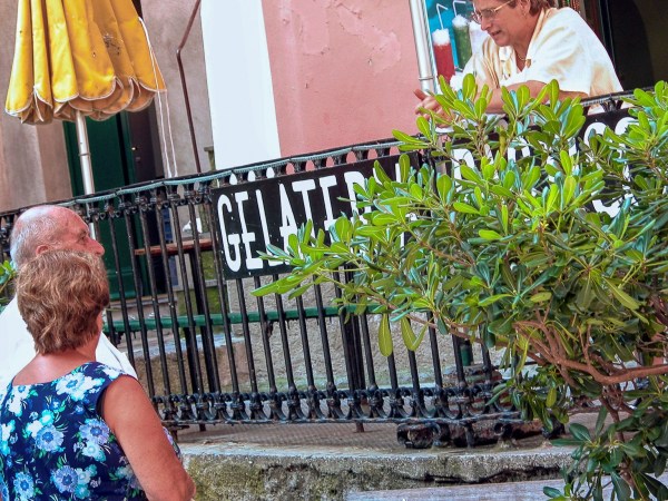 Italian ice shop owner talking with two elderly friends outside illustrating the duality flow