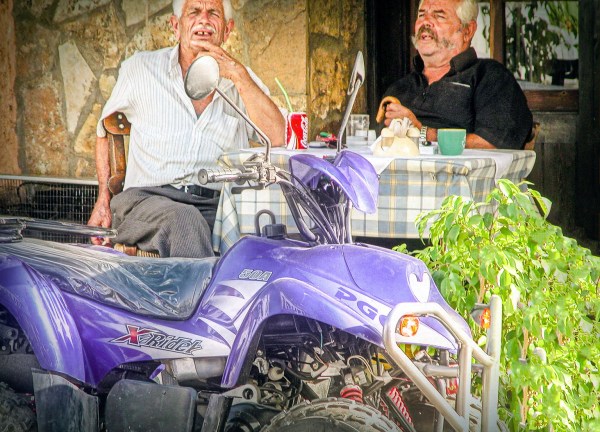 wo elderly men having breakfast together at an outdoor restaurant terrace serving area