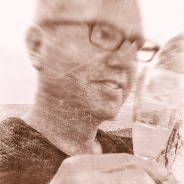 Sepia photo of Alexius Jorgensen smiling with a glass of limoncello in his hand